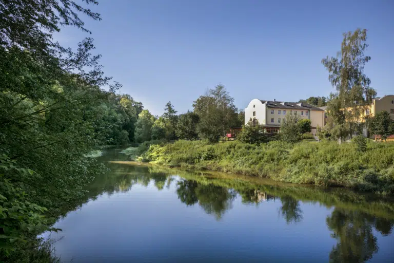 Hier seht ihr das JUFA Hotel Waldviertel von außen, direkt neben einem Fluss. JUFA Hotels bieten erholsamen Familienurlaub und unvergessliche Winter- und Wanderurlaube.