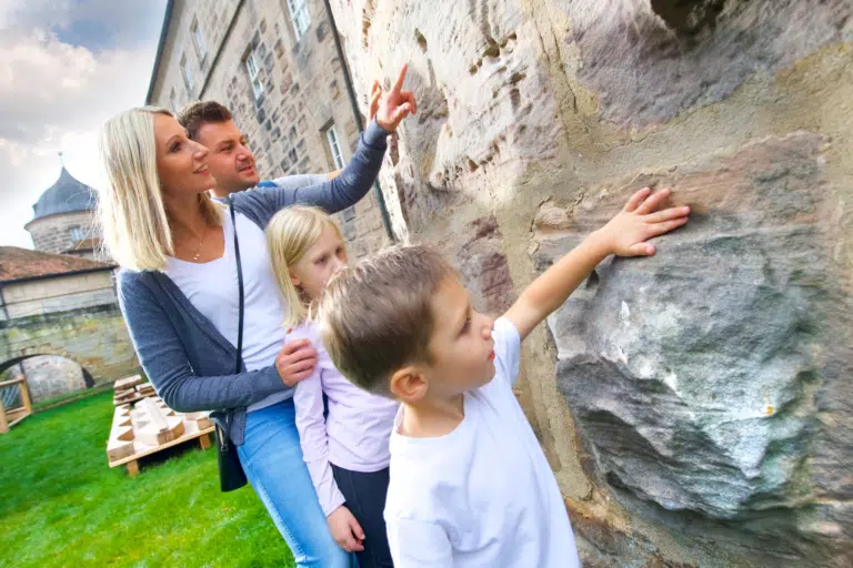 Ihr seht eine Familie an der Festungsmauer im JUFA Hotel Festung Rosenberg Kronach. Der Ort für kinderfreundlichen und erlebnisreichen Urlaub für die ganze Familie.