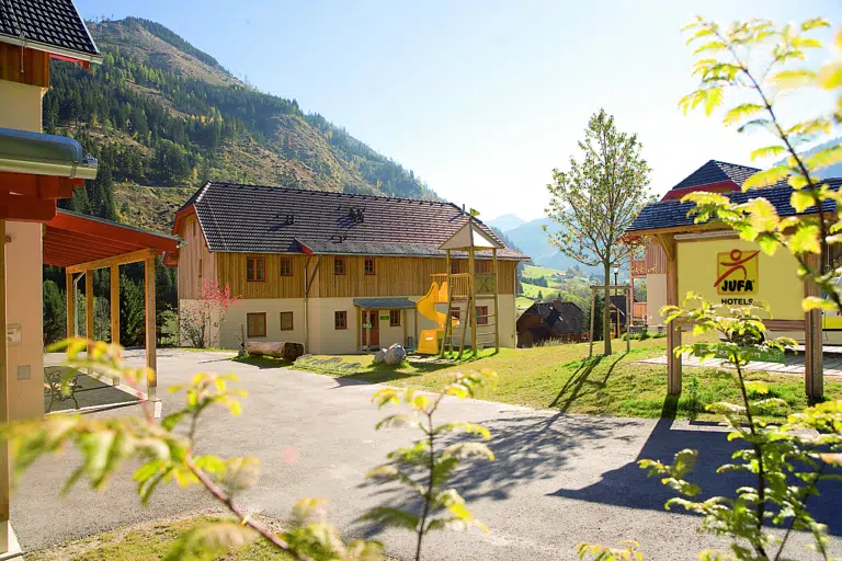 Aussenansicht vom JUFA Hotel Donnersbachwald - Almerlebnis im Sommer. Der Ort für erholsamen Familienurlaub und einen unvergesslichen Winter- und Wanderurlaub.