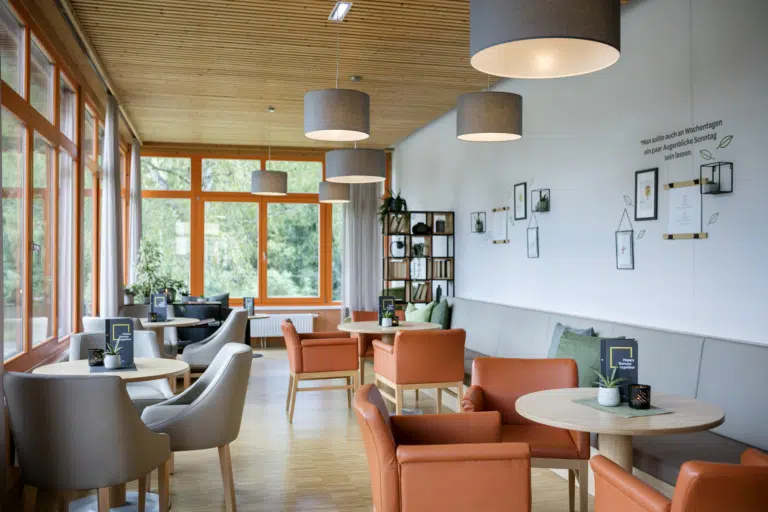 Ihr seht einen Sitzbereich mit einem Bücherregal im JUFA Hotel Waldviertel. Der Ort für erholsamen Familienurlaub und einen unvergesslichen Winter- und Wanderurlaub.