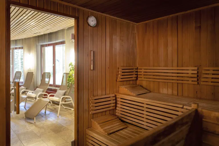 Ihr seht eine klassische Sauna mit Blick nach außen in den Wellness- und Saunabereich mit komfortablen Liegemöglichkeiten im JUFA Hotel Deutschlandsberg*** in der Steiermark.