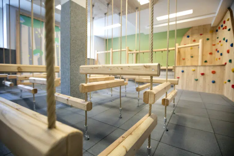 Ihr seht den Spielbereich mit einer Kletterwand und Balance-Blöcke im JUFA Hotel Waldviertel. Der Ort für kinderfreundlichen und erlebnisreichen Urlaub für die ganze Familie.