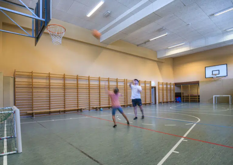 Ihr zwei Personen in der Sporthalle vom JUFA Hotel Altenmarkt*** Baskettball spielen.
