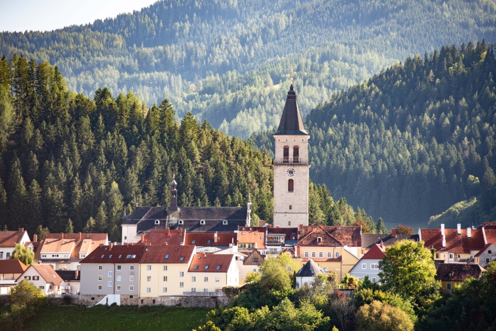 Ihr seht die Stadt Judenburg, Heimat des JUFA Hotel Judenburg***, im Sommer mit dem Stadtturm und Wälder im Hintergrund.