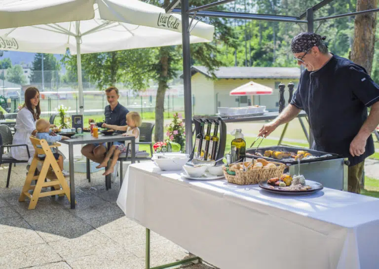 Ihr seht einen Mann beim Grillen auf der Terrasse des JUFA Hotel Altenmarkt***.