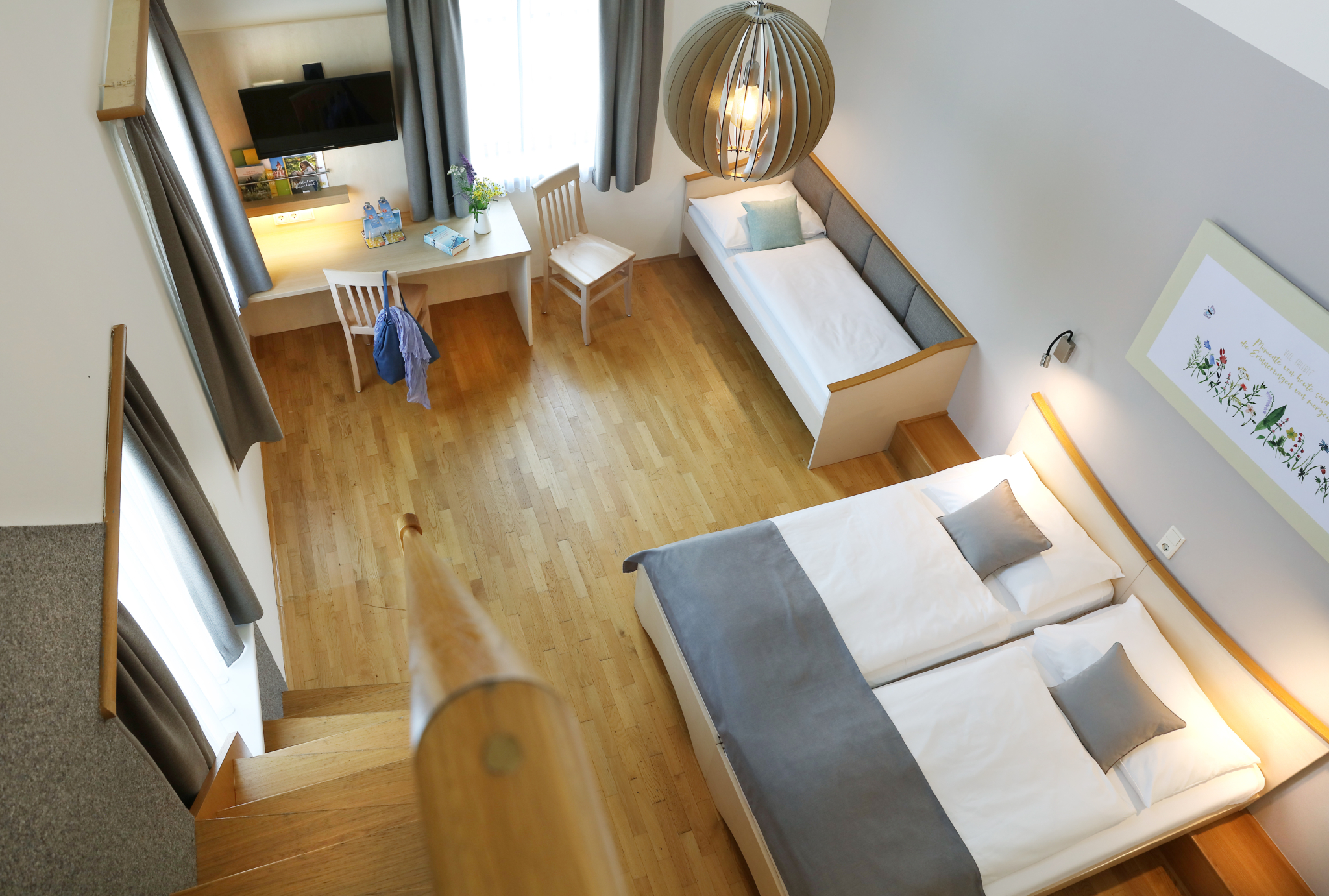 Sie sehen eine Couch und ein Doppelbett in einem Galeriezimmer im JUFA Hotel Pöllau - Bio-Landerlebnis. Der Ort für erholsamen Familienurlaub und einen unvergesslichen Winter- und Wanderurlaub.