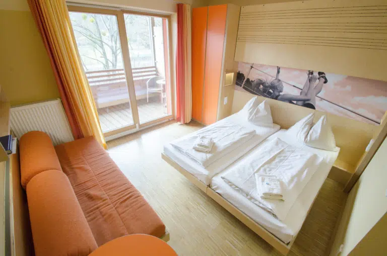 Doppelbett im Doppelzimmer im JUFA Hotel Leibnitz Sport-Resort mit Sofa