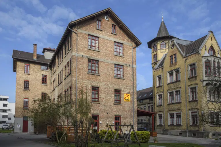 Aussenansicht mit Spielplatz im Sommervom JUFA Hotel Bregenz am Bodensee. Der Ort für tollen Sommerurlaub an schönen Seen für die ganze Familie.
