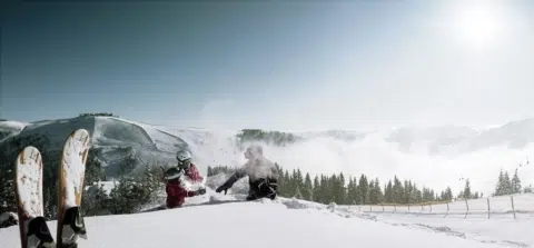 Ihr seht spielende Kinder im Schnee mit Schneeschuhen und Berge im Hintergrund auf der Schmitten