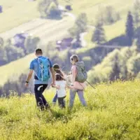 Ihr seht eine Familie beim Wandern im Laternsertal im JUFA Hotel Laterns – Klangholzhus***. Der Ort für erholsamen Familienurlaub und einen unvergesslichen Winter- und Wanderurlaub.