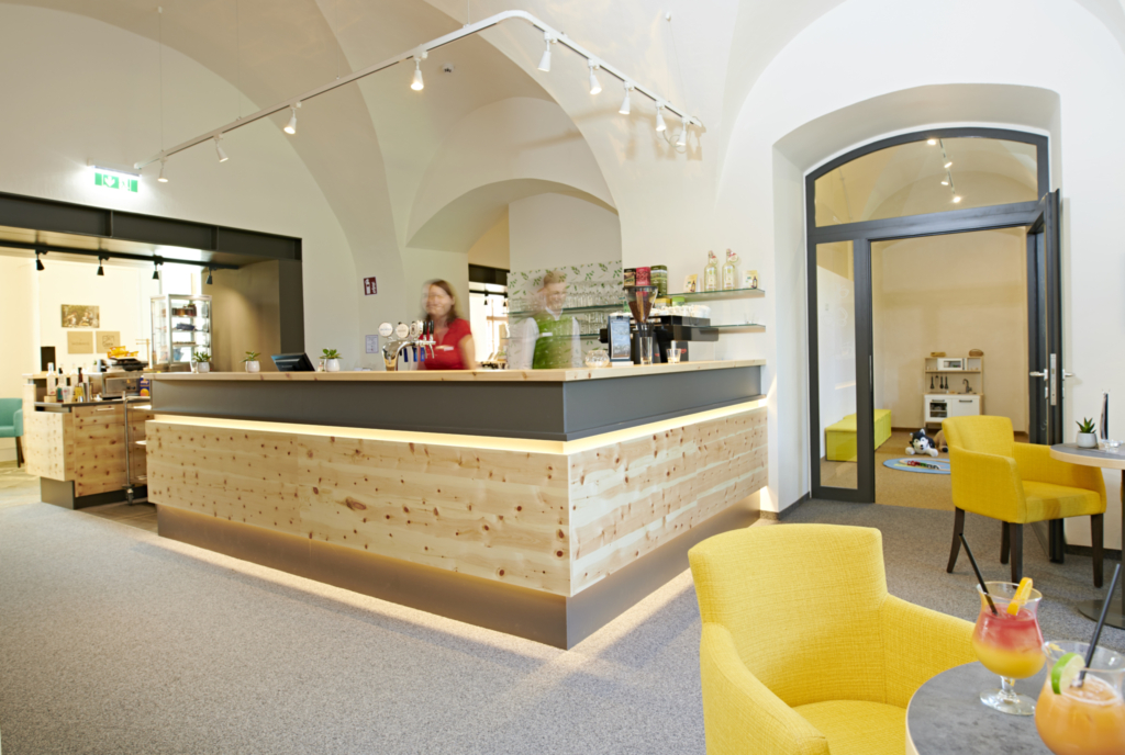 Ihr seht die Rezeption im JUFA Hotel Stift Gurk****. Der Ort für erlebnisreichen Natururlaub für die ganze Familie.