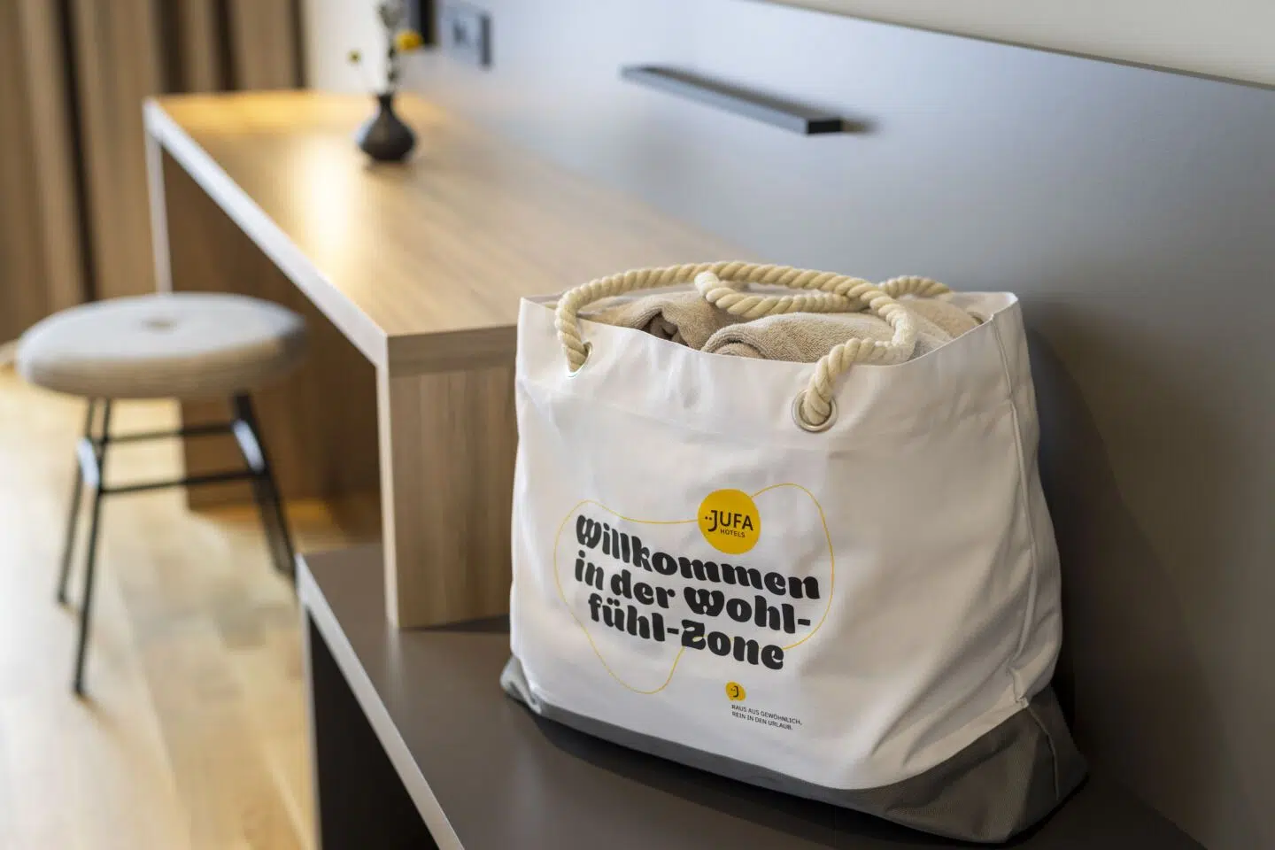 Ihr seht eine Badetasche im Zimmer des JUFA Hotel Bad Radkersburg**** mit Bademantel und Badeschlapfen.