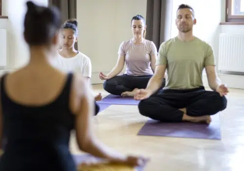 Ihr seht eine Gruppe, die sich gerade nach einer Yoga-Einheit im Kapitelsaal des JUFA Hotel Stift Gurk**** entspannt.