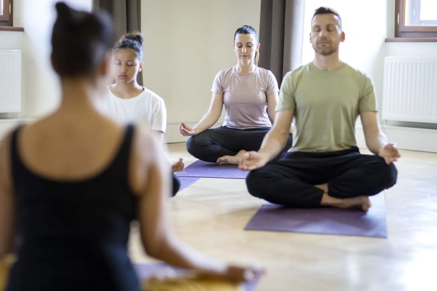 Ihr seht eine Gruppe, die sich gerade nach einer Yoga-Einheit im Kapitelsaal des JUFA Hotel Stift Gurk**** entspannt.