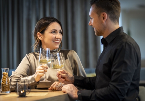 Ihr seht ein Pärchen bestehend aus Mann und Frau, die gerade mit einem guten Glas Weißwein auf einen romatischen Abend anstoßen.