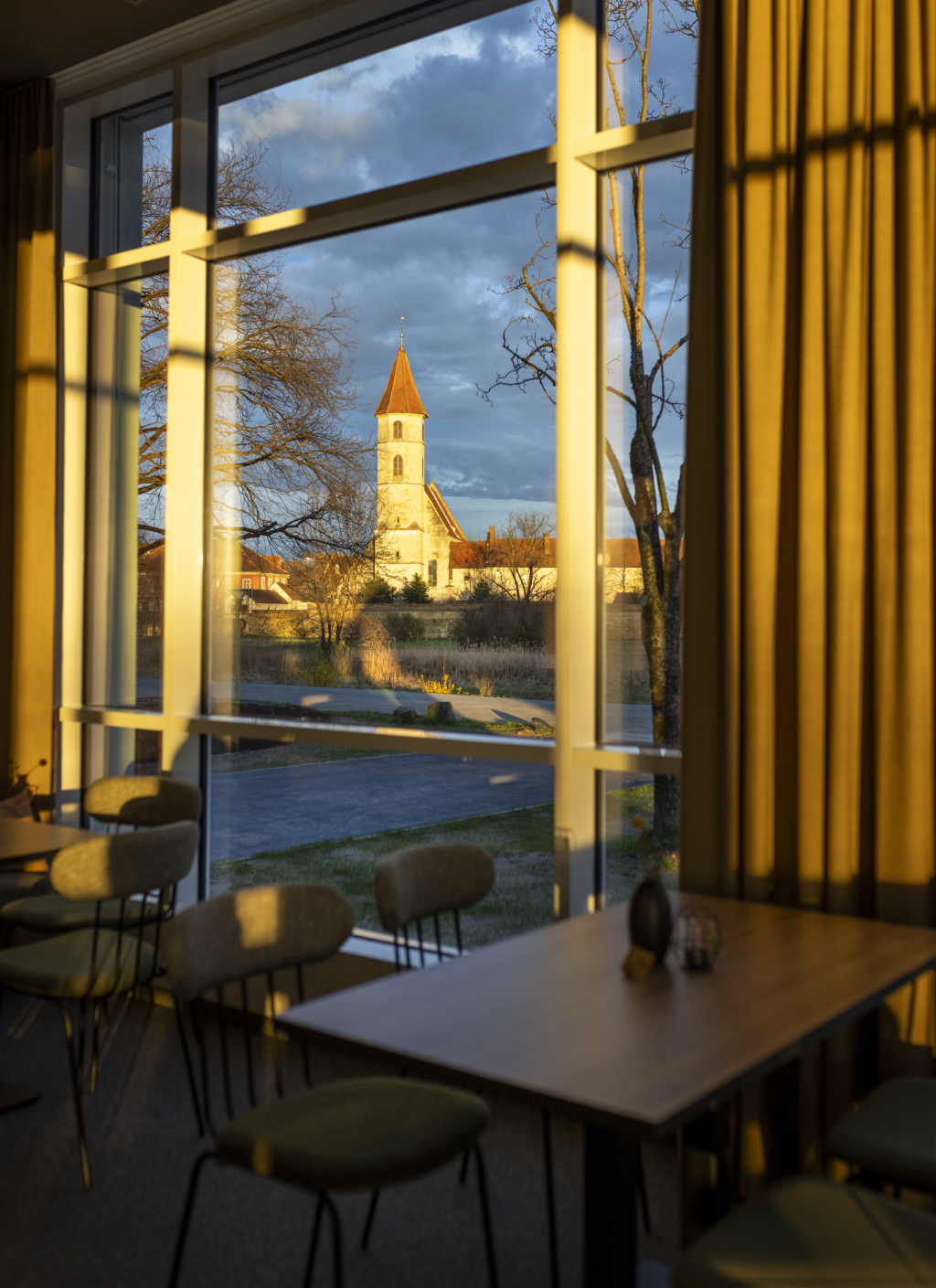 Ihr seht den Ausblick auf die Altstadt Bad Radkersburg in der Abendsonne vom Café & Restaurant Wandelhalle im Herzen des Kurparks im JUFA Hotel Bad Radkersburg