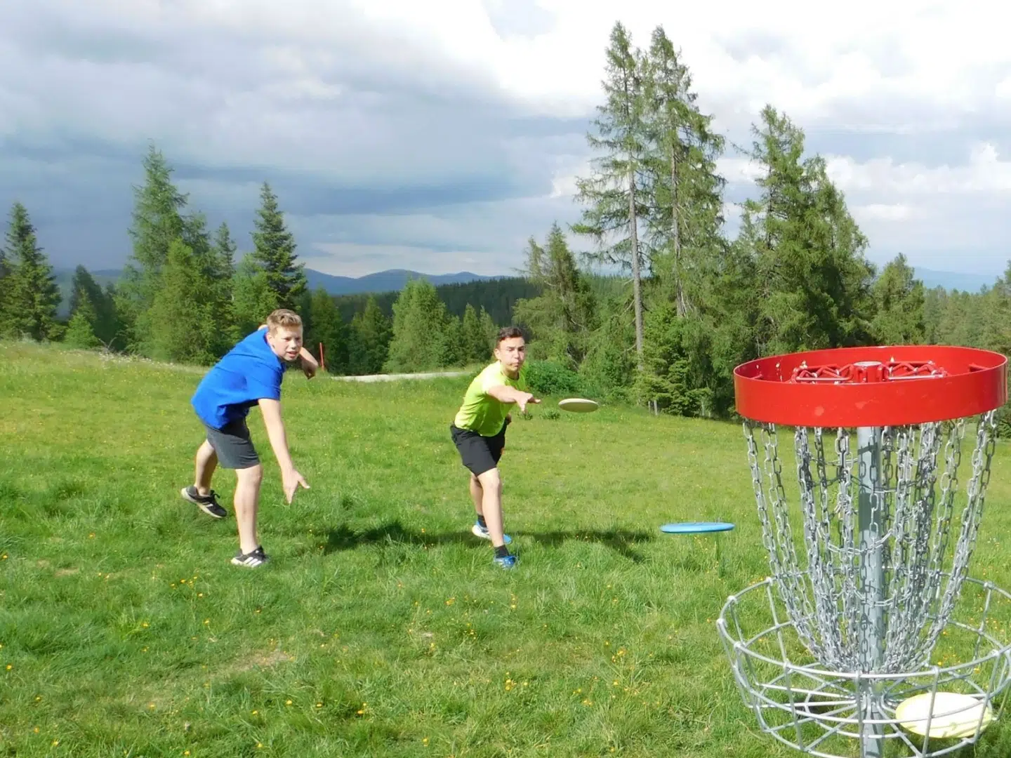 Ihr seht zwei Jungs beim Disc-Golf-Spielen auf der Hochrindl.
