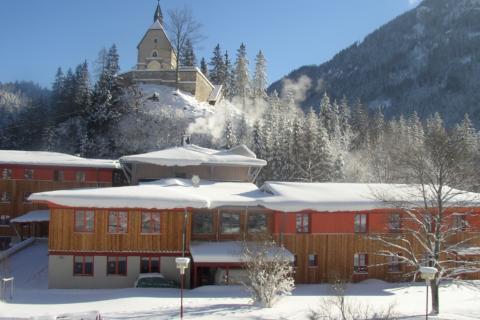 Aussenansicht vom JUFA Hotel Mariazell Sigmundsberg mit Hauskapelle im Winter. Der Ort für erholsamen Familienurlaub und einen unvergesslichen Winter- und Wanderurlaub.