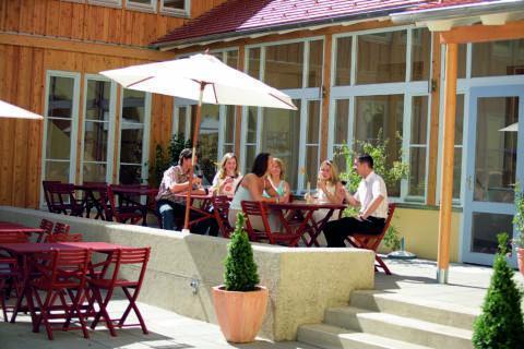 Gemütliche Sonnenterrasse mit Erwachsenen beim Weintrinken im JUFA Hotel Seckau. Der Ort für erholsamen Familienurlaub und einen unvergesslichen Winter- und Wanderurlaub.