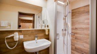 Badezimmer mit Dusche im JUFA Hotel Annaberg - Bergerlebnis-Resort. Der Ort für erholsamen Familienurlaub und einen unvergesslichen Winter- und Wanderurlaub.
