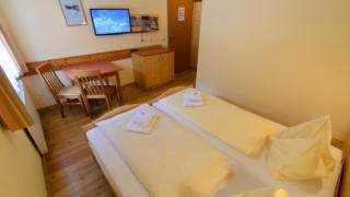 Doppelbett in einem Doppelzimmer im JUFA Hotel Donnersbachwald - Almerlebnis. Der Ort für erholsamen Familienurlaub und einen unvergesslichen Winter- und Wanderurlaub. 