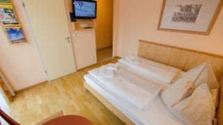 Doppelbett in einem Doppelzimmer im JUFA Hotel Gitschtal Landerlebnis. Der Ort für kinderfreundlichen und erlebnisreichen Urlaub für die ganze Familie.