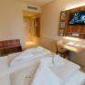 Bett im Doppelzimmer im JUFA Hotel Graz City mit TV. Der Ort für erlebnisreichen Städtetrip für die ganze Familie und der ideale Platz für Ihr Seminar.