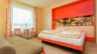 Doppelbett in einem Doppelzimmer im JUFA Hotel Wien City. Der Ort für erlebnisreichen Städtetrip für die ganze Familie und der ideale Platz für Ihr Seminar.