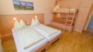 Betten im Familienzimmer medium im JUFA Hotel Kaprun mit Wandbild. Der Ort für erholsamen Familienurlaub und einen unvergesslichen Winter- und Wanderurlaub.
