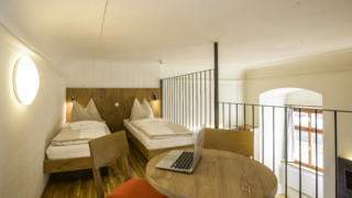 Betten im Galeriezimmer xlarge im JUFA Hotel Pyhrn-Priel mit Tisch. Der Ort für erfolgreiche und kreative Seminare in abwechslungsreichen Regionen.