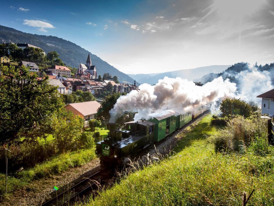 Dampfbummelzug Murtalbahn fährt in Murtal-Spielberg durch die Landschaft in der Nähe von JUFA Hotels. Der Ort für erholsamen Familienurlaub und einen unvergesslichen Winter- und Wanderurlaub.