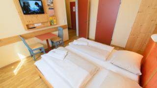 Doppelbett im Appartement xlarge im JUFA Hotel Lungau mit TV. Der Ort für erholsamen Familienurlaub und einen unvergesslichen Winter- und Wanderurlaub.