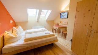 Doppelbett im Appartement im JUFA Hotel Murau mit TV. Der Ort für erholsamen Familienurlaub und einen unvergesslichen Winter- und Wanderurlaub.