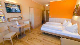 Doppelbett im Doppelzimmer im JUFA Hotel Neutal Landerlebnis mit TV. Der Ort für erlebnisreichen Natururlaub für die ganze Familie.