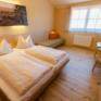 Doppelbett im Doppelzimmer im JUFA Hotel Neutal Landerlebnis mit Wandbild. Der Ort für erlebnisreichen Natururlaub für die ganze Familie.
