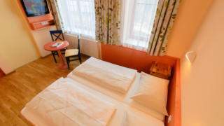 Doppelbett im Doppelzimmer im JUFA Hotel Nockberge Almerlebnis mit TV. Der Ort für erholsamen Familienurlaub und einen unvergesslichen Winter- und Wanderurlaub.
