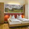 Doppelbett im Doppelzimmer im JUFA Hotel Pyhrn-Priel mit Wandbild. Der Ort für erfolgreiche und kreative Seminare in abwechslungsreichen Regionen.