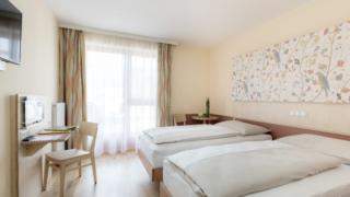 Betten im Doppelzimmer plus im JUFA Hotel Stubenbergsee mit Wandbild. Der Ort für tollen Sommerurlaub an schönen Seen für die ganze Familie.