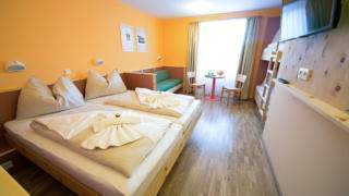 Doppelbett im Familienzimmer large im JUFA Hotel Planneralm Alpin-Resort mit TV. Der Ort für erholsamen Familienurlaub und einen unvergesslichen Winter- und Wanderurlaub.