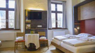 Doppelbett im Familienzimmer im JUFA Hotel Pyhrn-Priel mit Tisch. Der Ort für erfolgreiche und kreative Seminare in abwechslungsreichen Regionen.