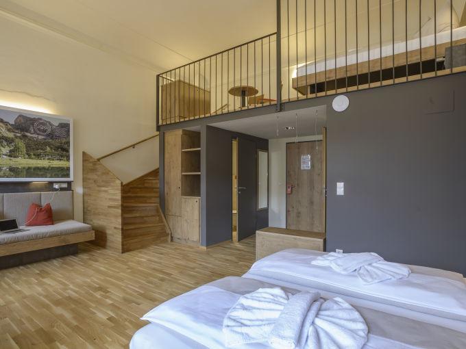 Doppelbett im Galeriezimmer xlarge im JUFA Hotel Pyhrn-Priel mit Sofa. Der Ort für erfolgreiche und kreative Seminare in abwechslungsreichen Regionen.