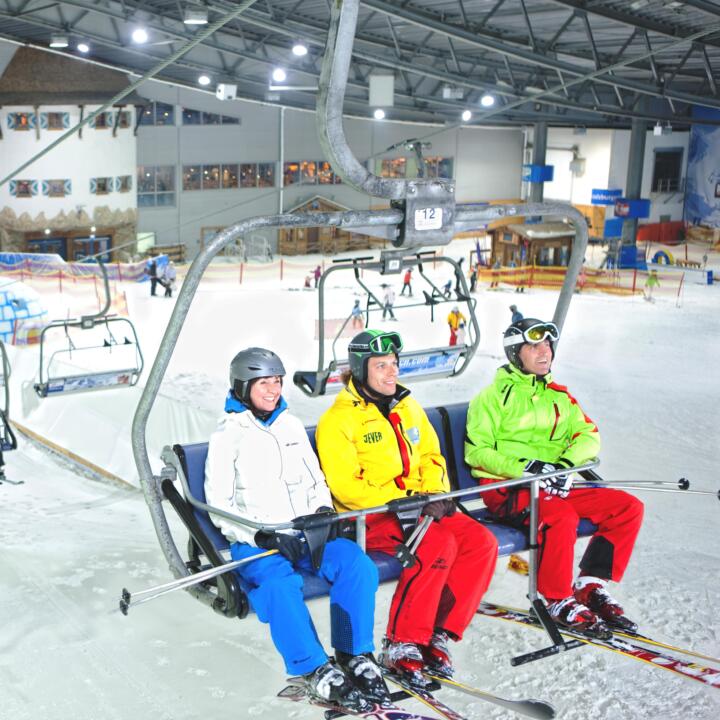 Erwachsene und Kinder auf Sessellift in der Skihalle Neuss in Nordrhein-Westfalen.  JUFA Hotels bietet kinderfreundlichen und erlebnisreichen Urlaub für die ganze Familie.