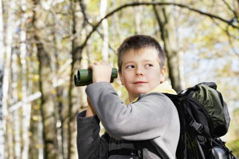 Junge mit Fernglas auf Entdeckungstour in der Natur. JUFA Hotels bietet Ihnen den Ort für erlebnisreichen Natururlaub für die ganze Familie.