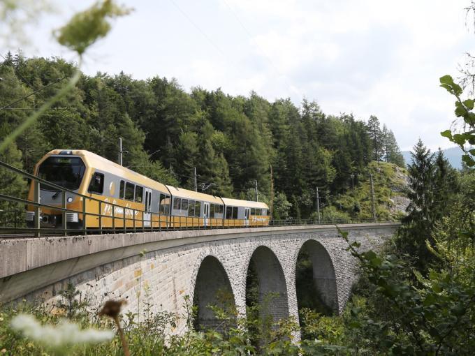Die Mariazellerbahn, alias die Himmelstreppe, fährt über eine Eisenbahnbrücke durch Landschaft in der Nähe von JUFA Hotels. Der Ort für erholsamen Familienurlaub und einen unvergesslichen Winter- und Wanderurlaub.