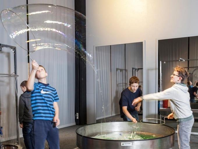 Kinder machen Riesenseifenblasen im Bubble Dom im Ökopark Hartberg. JUFA Hotels bietet kinderfreundlichen und erlebnisreichen Urlaub für die ganze Familie.