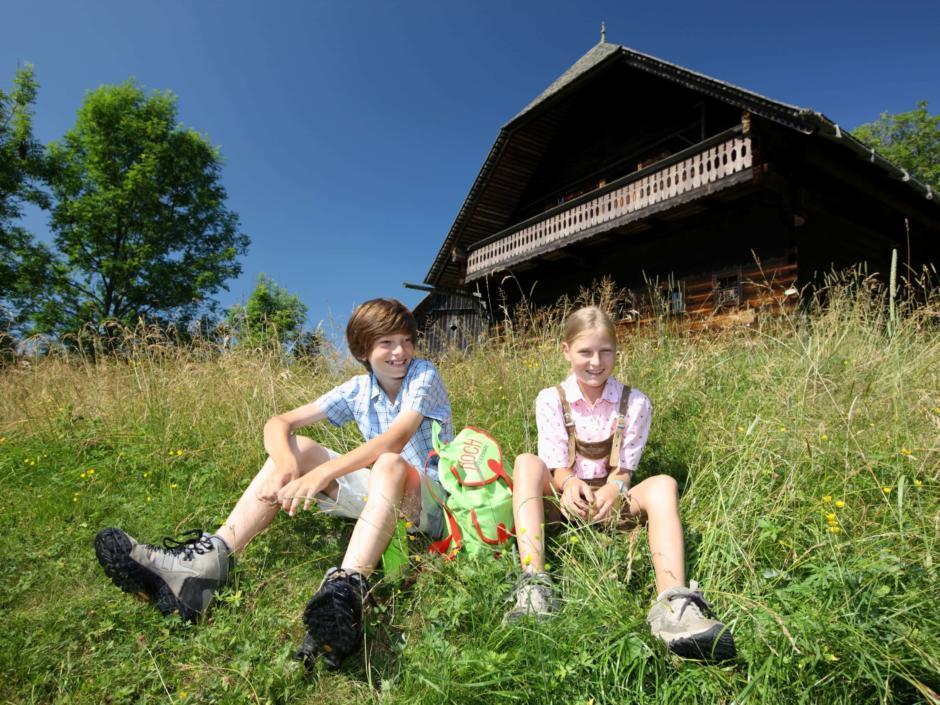 Kinder sitzen in einer Wiese in Peter Roseggers Waldheimat in der Steiermark. JUFA Hotels bietet Ihnen den Ort für erlebnisreichen Natururlaub für die ganze Familie.