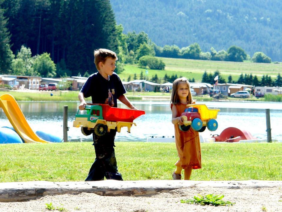 Zwei Kinder mit Sandspielzeug am Badestrand vom Pirkdorfer See in der Nähe von JUFA Hotels. Der Ort für erholsamen Familienurlaub und einen unvergesslichen Winter- und Wanderurlaub.