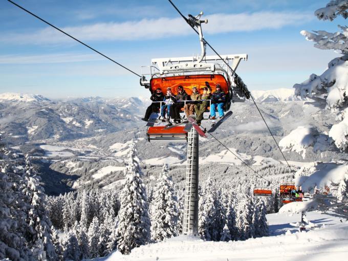 Snowboarder auf Sessellift im Skigebiet Semmering-Stuhleck in Niederösterreich. JUFA Hotels bietet erholsamen Familienurlaub und einen unvergesslichen Winterurlaub.