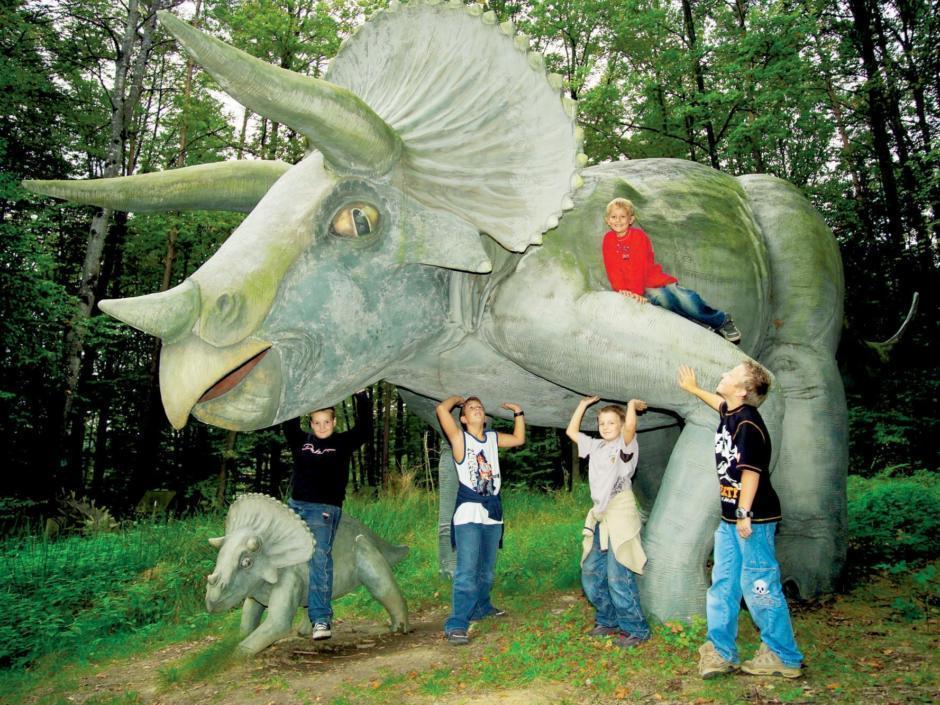 Kinder stehen vor Dinosauria im Styrassic Park in der Nähe von JUFA Hotels. Der Ort für erholsamen Familienurlaub und einen unvergesslichen Winter- und Wanderurlaub.