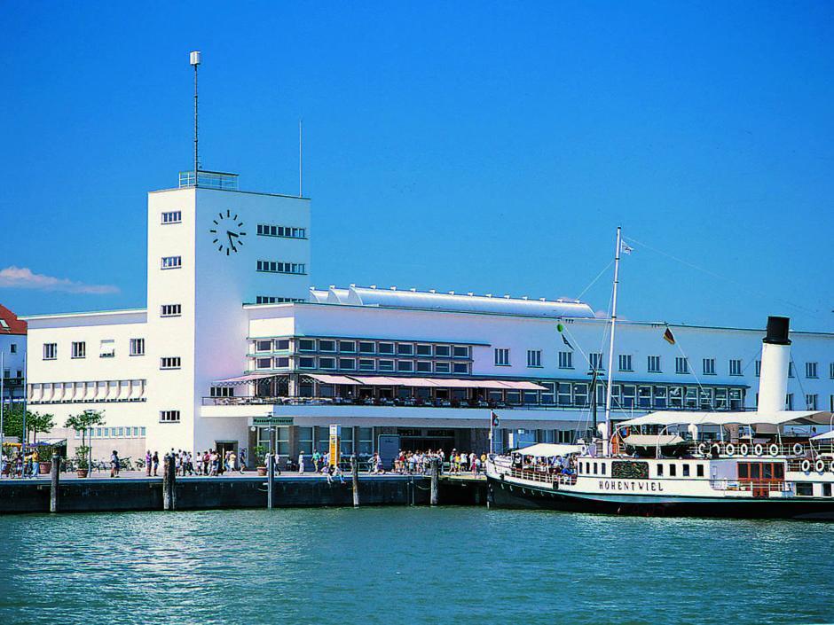 Sie sehe das Zeppelin Museum in Friedrichshafen am Bodensee mit einem Ausflugsboot. JUFA Hotels bietet kinderfreundlichen und erlebnisreichen Urlaub für die ganze Familie.